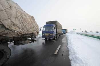 Some trucks drive slowly into the entrance of the Heliuye highway in Anhui Province, east China, Jan. 29, 2008. Most region in Anhui stopped snowing on Jan. 29. After all day working of removing ice and snow, most highways in Anhui reopened at present. (Xinhua Photo)