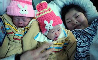 Cao Juan, a Chenzhou resident, smiles with her new-born twin girls beside her in a hospital in Chenzhou, Central China's Hunan Province on February 1, 2008. Snow and sleet have severely damaged the power facilities around the city since mid-January and the electricity crisis has caused major disruptionsto people there days before the Chinese Spring Festival. [Xinhua]