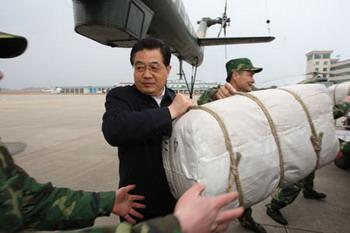 Chinese President Hu Jintao helps soldiers load relief supplies to a helicopter on Tuesday. (Xinhua Photo)