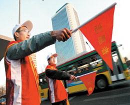Two volunteers direct traffic at an intersection in Beijing on March 2, 2008. More than one million Olympic volunteers will help maintain traffic order and patrol Beijing streets during China's parliament and political advisory body's annual sessions. [Photo: Beijing Morning Post]