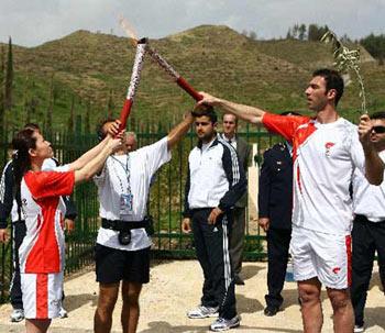 The first torchbearer, Greek taekwondo athlete Alexandros Nikolaidis(R), silver medalist in the Athens Olympics, kindles the torch in hand of former Chinese swimmer Luo Xuejuan(L), Athens Olympics gold medalist, during the torch relay of the Beijing Olympic Games in Olympia of Greece on March 24, 2008. (Xinhua Photo)