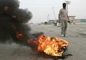 A fighter from the Mahdi Army militia stands guard near a burning tyre on a road in Baghdad's Sadr City March 26, 2008. Fourteen people were killed and more than 140 wounded in clashes between security forces and Shi'ite militants in Baghdad's Sadr City slum, a medical source said on Wednesday. (Xinhua/Reuters Photo)