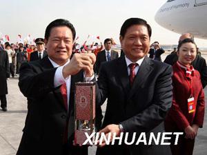 Welcoming the delegation at the airport was Zhou Yongkang,(L) member of the Standing Committee of the Political Bureau of the CPC Central Committee.He received the lantern fromLiu Qi(R), showed itto the welcoming crowds and passed it to special guards. The lantern was set down.