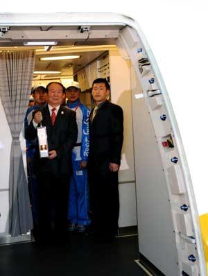 Jiang Xiaoyu (L front), the executive vice president of the Beijing Organizing Committee for the 2008 Olympic Games (BOCOG), walks out of the cabin with the lantern which holds the Olympic flame in his hands at the airport in London, capital of Britain, April 5, 2008. London is the fourth leg of the 2008 Beijing Olympic Games flame global tour.(Xinhua/Zhou Wenjie)
