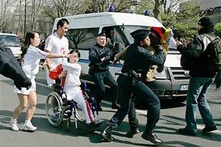 Torchbearer Jin Jing (in wheelchair), a Chinese wheelchair athlete, protects the torch from a protestor as she runs along the Seine River in the Beijing Olympic torch relay in Paris, April 7, 2008.