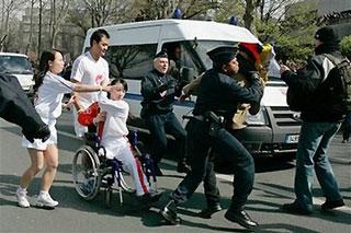 Torchbearer Jin Jing (in wheelchair), a Chinese Para-Olympic athlete, protects the torch to resist protestors' disruptions as she runs along the Seine River in the Beijing Olympic torch relay in Paris, April 7, 2008. [sohu.com]