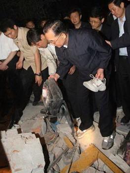 Chinese Pemier Wen Jiabao (C) picks up a shoe and a schoolbag at a ruined school in Dujiangyan city of southwest China's Sichuan Province May 12, 2008. Premier Wen flew into southwest China's Sichuan Province on Monday. (Xinhua Photo)