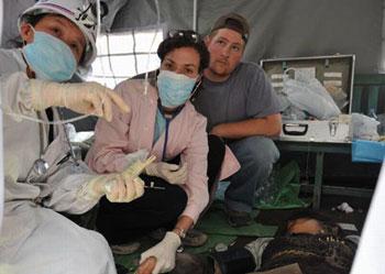 The U.S. volunteers who called themselves as Kelsey (2nd L) and Mu Yongshi (3rd L) assist a doctor to treat an injured in the quake-hit Beichuan County in southwest China's Sichuan Province, May 14, 2008. Some foreigners who work or study in Sichuan came to Beichuan to help the rescue and relief works in the devastated region.  (Xinhua Photo)