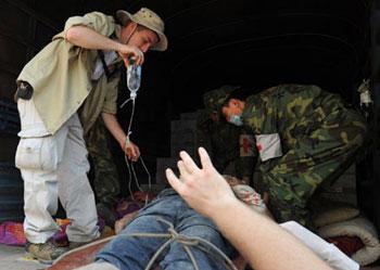The U.S. volunteer who called himself as Guo Aide (L) assists a doctor to treat an injured in the quake-hit Beichuan County in southwest China's Sichuan Province, May 14, 2008.  (Xinhua Photo)