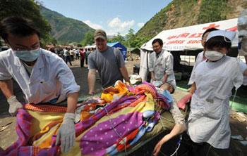 The U.S. volunteer who called himself as Mu Yongshi (2nd L) assists doctors to transfer an injured in the quake-hit Beichuan County in southwest China's Sichuan Province, May 14, 2008. (Xinhua Photo)