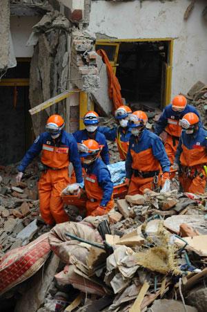 Members of the Japanese rescue team carry the body of a victim at Qiaozhuang Town of Qingchuan County in the quake-stricken southwest China's Sichuan Province, May 17, 2008. Japanese earthquake rescuers found two corpses in a collapsed six-floor building in Qiaozhuang at 7:25 am after 16 hours rescue operation. (Xinhua/Li Tao)