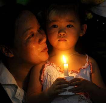 A girl holds a candle during a candlelight vigil to commemorate earthquake victims at Hongshan Park of Wuhan, Central China's Hubei Province, May 17, 2008.[Xinhua]