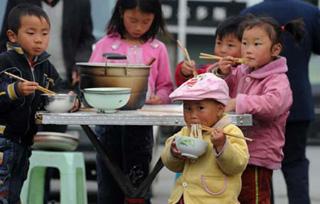 Children have their meals in Maoxian county, the quake-hit Sichuan Province, southwest China, May 18, 2008. Water supply and telecom have been resumed in Maoxian county, and survivors here are well settled. (Xinhua Photo)