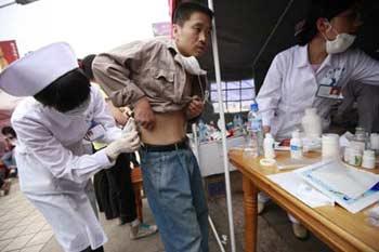 A medical worker treats a victim at the temporary rescue center of the quake-hit Hanwang Township of Mianzhu City, southwest China's Sichuan Province, May 17, 2008.(Xinhua Photo)