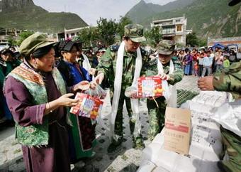 Soldiers hand out relief materials to villagers of Ganbao Tibetan ethnic village in quake-hit Lixian County, southwest China's Sichuan Province, May 22, 2008. Three helicopters of Chengdu air force on Thursday transported 26 tents, 200 quilts and 400 cotton-padded clothes to Tibetan villagers here.(Xinhua Photo)