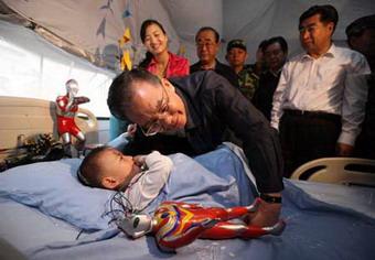 Chinese Premier Wen Jiabao listens to Lang Zheng, a boy injured in last week's 8.0-magnitude earthquake, at NO. 404 hospital in Mianyang, the quake-hit southwest China's Sichuan Province, May 23, 2008.(Xinhua Photo)
