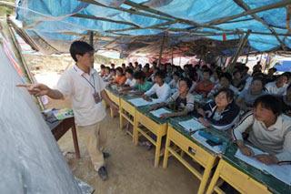 Students of Fanba Middle School attend class in a tent in Wenxian County of Longnan City, northwest China's Gansu Province, May 22, 2008. The school resumed class on May 19 after a hiatus because of the May 12 quake hitting northwest and southwest China. (Xinhua Photo)