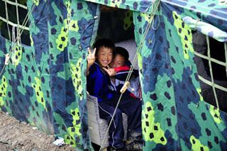 Two boys gesture in a tent at a temporary resettlement for the earthquake victims in Baoshan Village in Longmenshan Township of Pengzhou City, southwest China's Sichuan Province, May 25, 2008. There are some 800 people living in about 90 tents at this temporary resettlement now. PLA soldiers, militia and volunteers try their best to make convenience and provide service for the victims from the quake-hit areas.(Xinhua/Ren Yong)