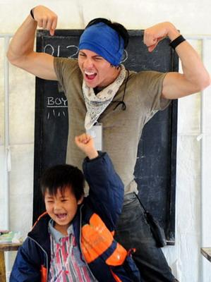 A volunteer from the United States plays games with Chinese children during an English class in a makeshift classroom in quake-affected Anxian County of Sichuan Province May 29, 2008. Two US volunteers arrived at the county on Thursday to help with English lessons. [Xinhua]