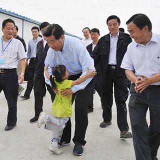 China's top political advisor Jia Qinglin tries to hold a girl in arms at a relief station in Dujiangyan City, southwest China's Sichuan Province, May 30, 2008.Jia, National Committee of the Chinese People's Political Consultative Conference (CPPCC) chairman and a member of the Standing Committee of the Political Bureau of the Communist Party of China (CPC) Central Committee, came to the epicenter Yingxiu Town and worst-hit Dujiangyan City on Friday to direct the relief work and express his sympathy and solicitude for people affected by the 8.0-magnitude quake on May 12. (Xinhua Photo)
