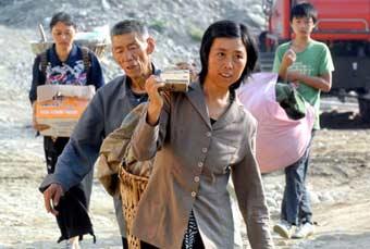 Residents carry their belongings to temporary plank houses at Huilong Village in Qingchuan County, southwest China's Sichuan Province, June 5, 2008. Around 500 quake-affected residents moved to temporary plank houses in Qingchuan County on June 5.(Xinhua Photo)