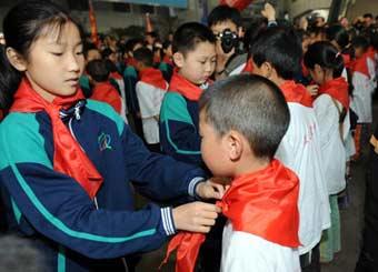 Students of Mingzhu Primary School tie red scarves for students from the quake-hit Sichuan Province in southwest China, in Jinan, capital of east China's Shandong Province, June 5, 2008. A total of 809 students from Leigu Town of Sichuan's Beichuan County, one of the most serious quake-hit areas, arrived in Jinan Thursday to restart their study in four schools.(Xinhua Photo)