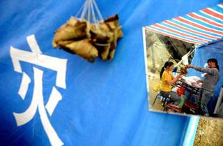 Two women prepare "Zongzi", a traditonal food for the Dragon Boat Festival, near their tent in Yingxiu Town, Wenchuan County, southwest China's Sichuan Province, June 8, 2008. Food including "Zongzi" and salted duck eggs, the indispensable food for the Chinese during the Dragon Boat Festival, was donated to the earthquake-hit areas to celebrate the traditional festival. (Xinhua Photo)
