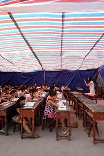 Sixth graders attend class in a tent at Chengguan No.2 elementary school in Wenxian county, Longnan city, northwest China's Gansu Province June 11, 2008. About 90 percent of the 2,964 middle schools and elementary schools suspended in the quake-hit Longnan city have resumed classes by now. The local government is still working hard to help reopen schools and kindergartens in remote villages and mountainous areas. (Xinhua Photo)