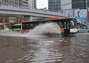 A bus splashes through a flooded street in Guangzhou, capital of south China's Guangdong Province, June 14, 2008. A dozen people were killed and millions were affected as rainstorms continued to lash south China over the past several days.(Xinhua Photo)