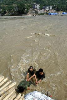 Soldiers from airborne force eliminate danger in flashy stream at Nanba Town, Pingwu County of Mianyang City, in southwest China's Sichuan Province, on June 12, 2008. The airborne troops built up a "life bridge" above a torrential stream that separate Nanba Town and the outside areas and take guard around the bridge day and night against any contingency that could break it. (Xinhua Photo)