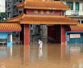 A man walks in front of a sugar refinery submerged in the flood caused by heavy rainstorm in Luorong Town of Luzhai County, southwest China's Guangxi Zhuang Autonomous Region, June 13, 2008. A new round rainstorm that began on June 11 hit several counties and cities in Guangxi and caused flood in some districts. (Xinhua Photo)