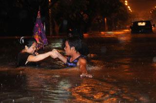 Two citizens cross over the inundated Xihuan Road, in an emergent displacement move, at Liuzhou City, southwest China's Guangxi Zhuang Autonomous Region, June 12, 2008. Local weather department issued red pre-alert signal for rainstorm on June 12th and 13th. Two days' heavy precipitations that hit Liuzhou has caused severe inundation, particularly acute in lower parts of the city proper, that left pedestrians and vehicles stranded.(Xinhua Photo)