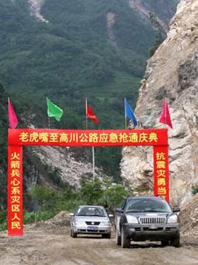 Two cars drive on a trial use of the road which has been repaired and reopened to traffic in Anxian County of quake-hit Sichuan Province, southwest China, June 15, 2008. The 18-km road linking towns of Suishui and Gaochuan, was once called the 