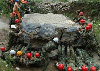 Soldiers remove a huge stone that poses threat to public in Wudu Town of Jiangyou City, southwest China's Sichuan Province, June 16, 2008. Roads are swamped by a massive landslide on Monday leaving exceeding 1,000 peopel of two villages trapped without life supplies. It took three hours for the soldiers to get through the road.(Xinhua Photo)