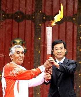 Gonpo (L), 75-year-old Tibetan mountaineering hero and the first torchbearer, receives the torch from Qin Yizhi, secretary of the Lhasa city committee of the Communist Party of China, during the 2008 Beijing Olympic Games torch relay in Lhasa, capital of southwest China's Tibet Autonomous Region, on June 21, 2008. (Xinhua Photo)