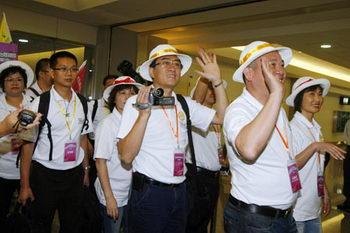 The first group of mainland tourists of the day to arrive in Taiwan from Guangzhou, wave to reporters at the Taoyuan International Airport July 4, 2008. [Agencies]