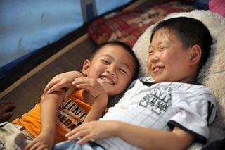 Lin Dicheng (L) plays with a friend in a tent at Guantan Village in Jushui Town of Anxian County, southwest China's Sichuan Province, July 8, 2008. Three-year-old Lin's parents were dead in the May 12 quake when they were working in the town. More than 1,000 children in Sichuan became orphans after the quake devastated many areas of the province. Most of the orphans have been taken home by their relatives and have gradually recovered from the sufferings. More and more children have regained smile and confidence with the help from their relatives and the society. (Xinhua Photo)