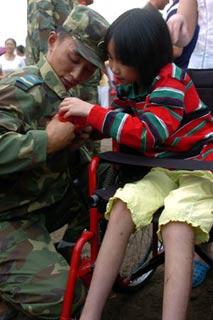 Chen Yangmeng, a 11-year-old girl survived the fatal earthquake happened in May 12, presents a flower to show her respects to a soldier of Chinese People’s Liberation Army (PLA) in Shifang of southwest China’s Sichuan Province on July 20, 2008. The first batch of PLA soldiers withdraw from the quake-hit city of Shifang on Sunday. (Xinhua Photo)