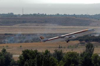 A plane takes off near the site where a Spanish plane caught fire at Madrid's Barajas airport, Spain, Aug. 20, 2008. (Xinhua Photo)