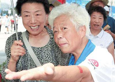 An elderly volunteer gives directions yesterday to a woman tourist at Xidan Cultural Square. (Photo: China dDily)