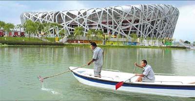Workers clean up the artificial lake surrounding the Bird's Nest. [China Daily]
