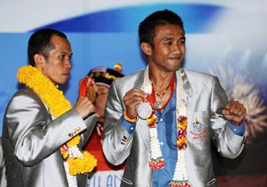 Somjit Jongjohor of Thailand (L), who won the gold medal of the Men's Fly (51kg) of the 2008 Beijing Olympic Games boxing event, and Manus Boonjumnong of Thailand, who won the silver medal of the Men's Light Welter (64kg) bout of the 2008 Beijing Olympic Games boxing event, gesture to people upon their arrival at the Bangkok International Airport in Bangkok, capital of Thailand, Aug. 25, 2008. The Thailand delegation claimed 2 golds and 2 silvers, ranking 31st at the gold medal standings of the Beijing Olympics.(Xinhua/Ling Shuo)