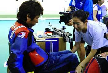 South Korean athlete Lee Ji-Seok celebrates with his wife Park Kyoung-Sun stands behind after the final of Mixed R4-10m Air Rifle Standing SH2 of Beijing Paralympic Shooting event at the Beijing Shooting Range Hall Sept. 11, 2008. Lee got the gold medal in the event with a total of 704.3. This is Lee's second gold medals in the Beijing 2008 Paralympic Games. Lee was seriously injured in a traffic accident in 2001. It was Park, a nurse then, who took good care of him during his rehabilitation and later encouraged him to train for shooting.(Xinhua/Ren Yong)