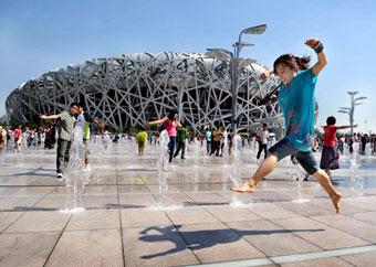 A girl plays with the music fountains in front of the National Stadium, or the Bird's Nest during the 2008 Beijing Paralympic Games September 11, 2008. [Xinhua]