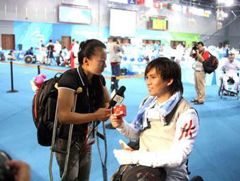 Chinese wheelchair fencer Jin Jing(L) makes an interview with Chan Wing Kin of Chinese Hong Kong after men's individual foil preliminary match of the Beijing 2008 Paralympic Games wheelchair fencing event in Beijing, China, September 14, 2008. (Xinhua/Zhang Lei)