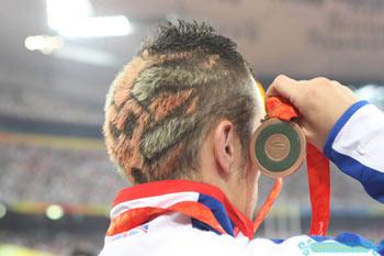 A British athlete, who wins the bronze in men's 200m T44 final, stands on the podium during the medal ceremony at the National Stadium, also known as the Bird's Nest, during the Beijing 2008 Paralympic Games September 13, 2008. His bizarre hairdo attracts much attention from media and spectators.[Sohu.com]