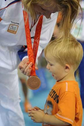 A sitting volleyball player of the Netherlands shares the victory with her little son after the medal ceremony, September 14, 2008. The Netherlands beats Slovenia to win the bronze in women’s sitting volleyball competition.[Xinhua]