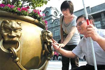 Shi Jing (right) touches a giant bronze flowerpot on Qianmen Street yesterday.(China Daily Photo/Wang Jing)