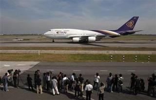 Journalists and airport officials watch the first Thai Airways flight with passengers, arriving from Phuket, land at Bangkok's Suvarnabhumi Airport December 3, 2008, after a week long anti-government protest paralyzed air travel.(Chaiwat Subprasom/Reuters)