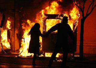A couple runs to escape a fire from a bus station booth during riots in Athens Dec. 7, 2008. Riots raged in several cities after police shot dead a teenage boy in the Greek capital, in the Mediterranean nation's worst civil disturbances in years. (Xinhua/Reuters Photo)